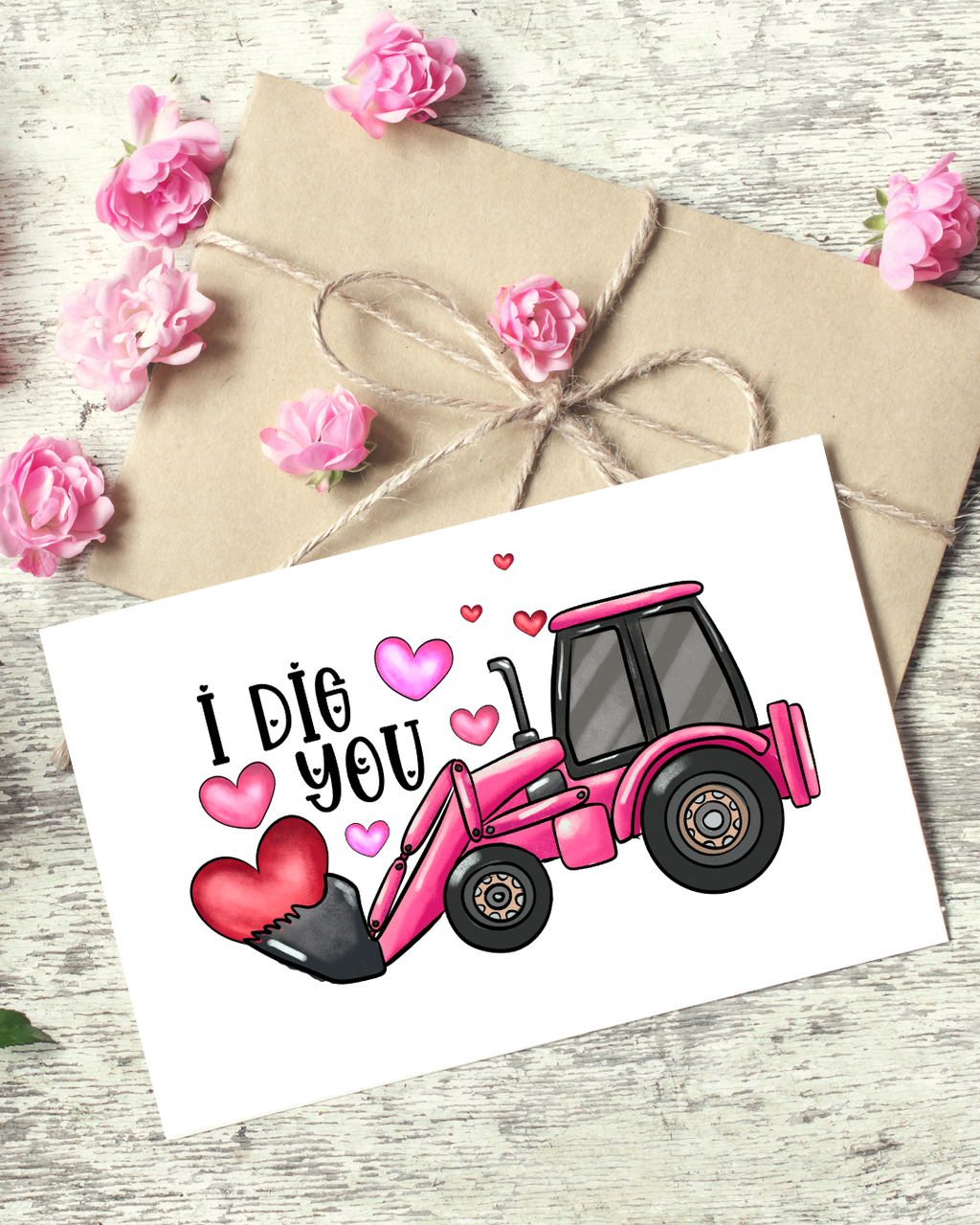 Pink bulldozer with 'I Dig You' text on a card, surrounded by flowers and brown paper.